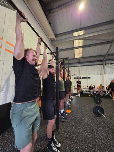 A group of people performing pull-ups in a gym setting.